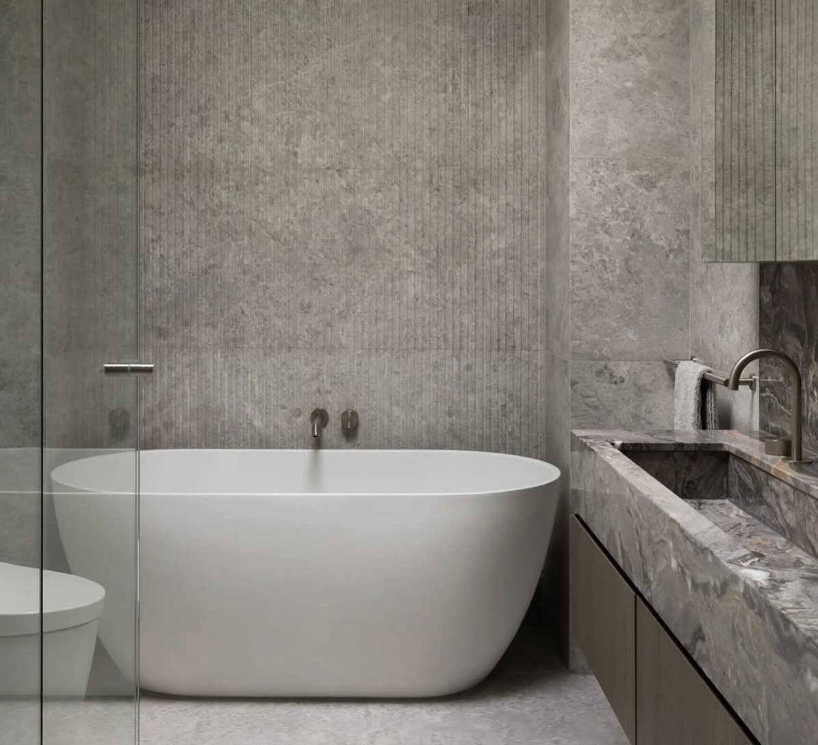 High-end grey stone bathroom with freestanding bath and stone vanity